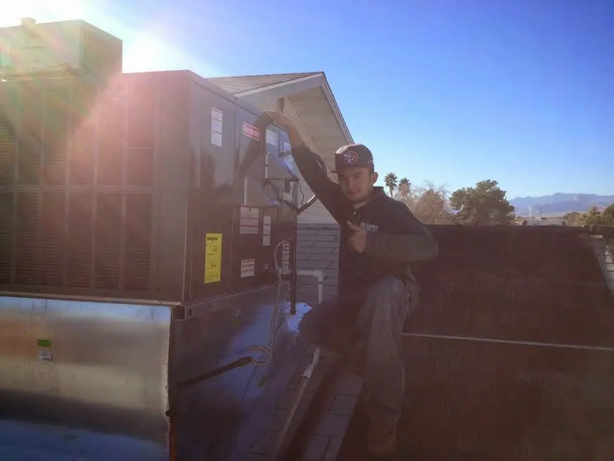 HVAC technician performing HVAC Inspection on a rooftop unit in Adelanto